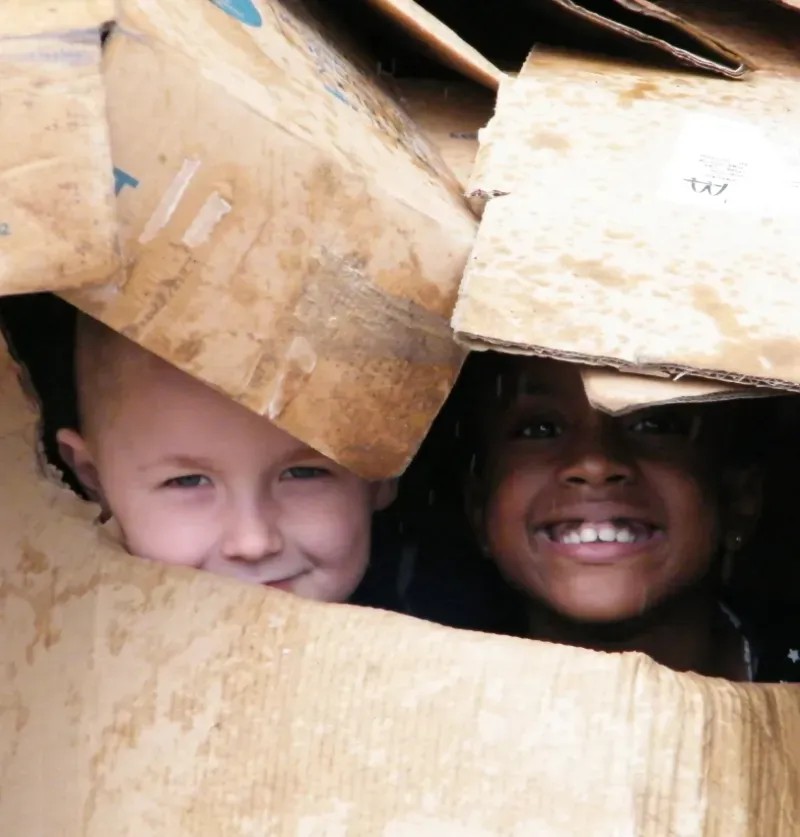 Two boys faces peering out of cardboard boxes