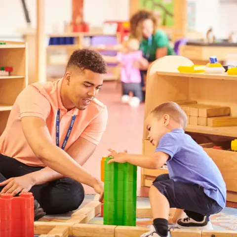 Male nursery worker with child in setting