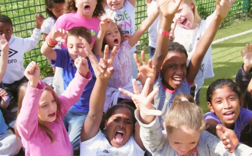 Children holding hands up and smiling